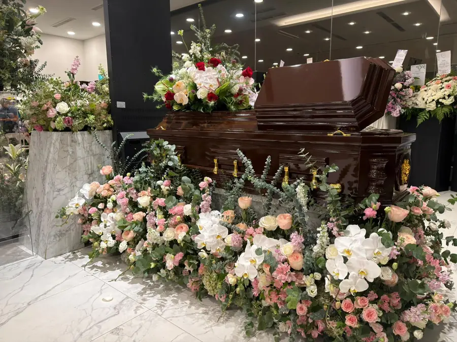 Freethinker funeral casket with floral tributes side view