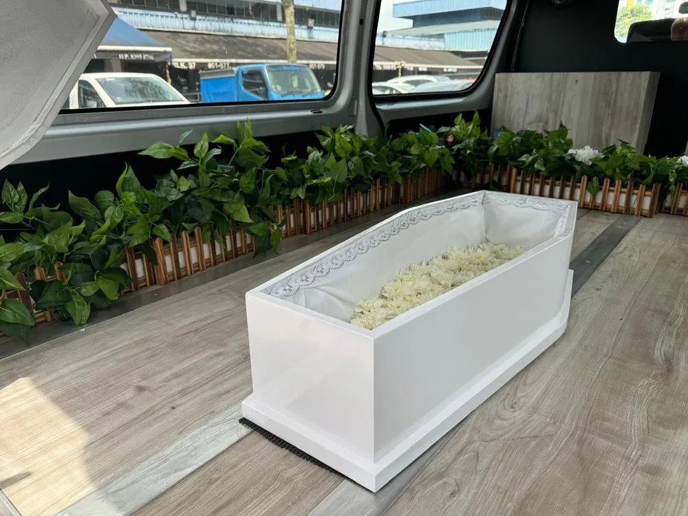 White infant casket with flowers inside the hearse