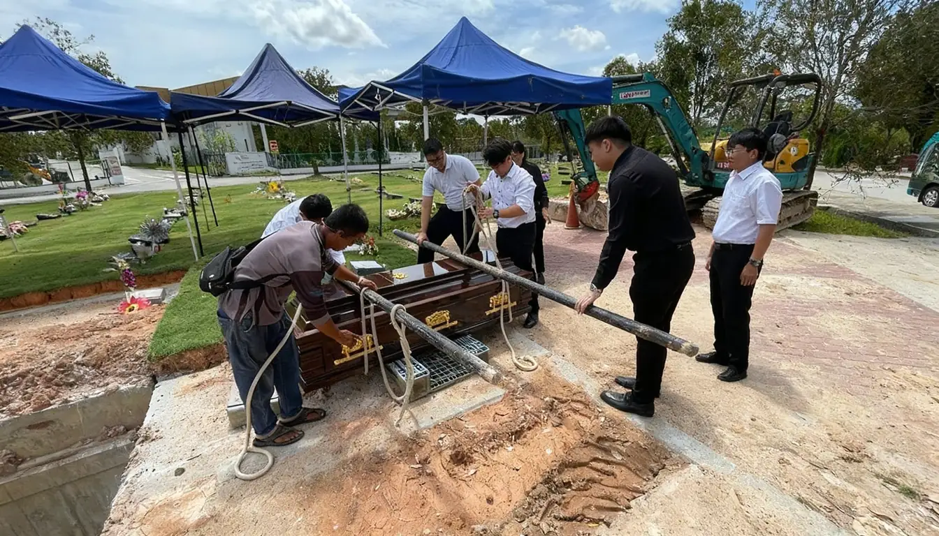 Funeral staff lowering a casket into a burial vault using ropes at Choa Chu Kang Cemetery